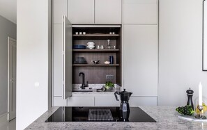 A modern kitchen with a built-in dishwasher, a coffee machine, and a sink. - Luxury Apartment in a Prime Location with Netflix (Helsinki)