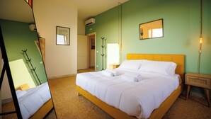 Una camera d'albergo con un letto, uno specchio, un comodino, una lampada e un quadro appeso al muro.