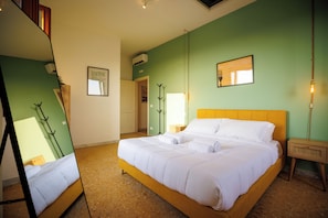 Ein Hotelzimmer mit Bett, Spiegel, Nachttisch, Lampe und einem Bild an der Wand.