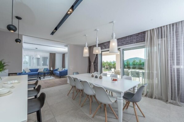 Un'area pranzo moderna con tavolo bianco, sedie grigie e lampade a sospensione.