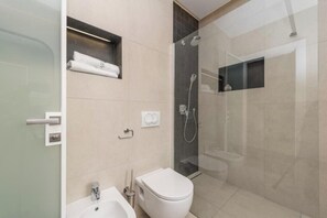 Moderni kylpyhuone, jossa on lasinen suihkuseinä, wc ja pesuallas.