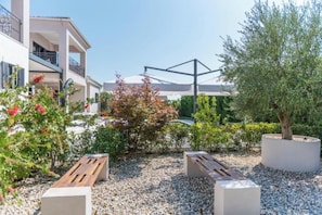 A courtyard with outdoor seating, a pergola, and a building with balconies.