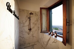 Ein Badezimmer mit Dusche, einem Fenster mit Blick und einer Marmorwand.
