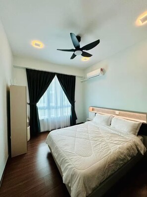 A hotel room with a bed, a ceiling fan, a window with curtains, and an air conditioning unit.