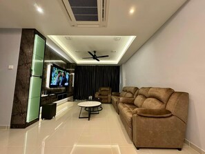 A modern living room with a flat-screen TV, a ceiling fan, a sofa, a coffee table, and a TV stand. - Trival Luna Homestay @ Sri Indah Sandakan (Sandakan)