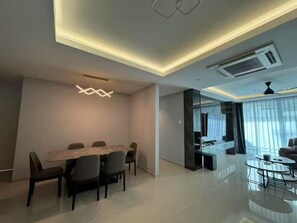 A modern living room with a dining area, a large window with curtains, a ceiling fan, and a built-in air conditioning unit. - Trival Luna Homestay @ Sri Indah Sandakan (Sandakan)