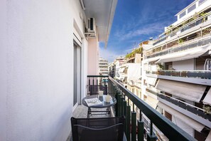 Un balcón con una mesa y sillas, con vista a una zona residencial con varios edificios.