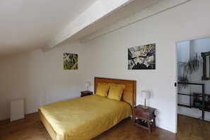 A bedroom with a bed, two bedside tables, a wooden headboard, and two wall-mounted paintings. - Les Airis, ecological vacation rental (Avignon)