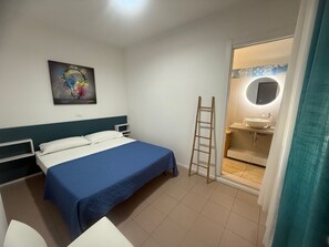 Ein Hotelzimmer mit Bett, Nachttisch, Wand-TV, Badezimmer mit Waschbecken und Spiegel sowie einer Wendeltreppe.