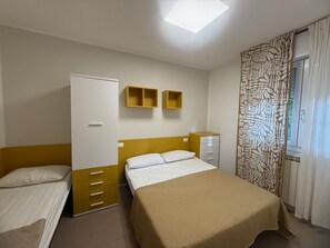 A bedroom with a bed, a wardrobe, a desk, and a window with curtains. - Spacious Apartment Near the Beach in Rosolina (Rosolina)