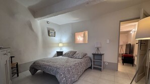 Ein Schlafzimmer mit einem Bett, zwei Nachttischen, einer Lampe, einem Spiegel und einem Kleiderschrank.