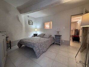 A bedroom with a bed, two bedside tables, a lamp, a mirror, and a wardrobe. - Vrbo Property (Saint-Paul-de-Vence)