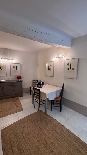 A dining area with a table, chairs, a ceiling light fixture, and artwork on the walls. - In the heart of the historic village, you'll find absolute peace and quiet. (Saint-Paul-de-Vence)