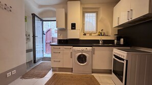 A compact kitchen with a washing machine, a stove, and a sink. - In the heart of the historic village, you'll find absolute peace and quiet. (Saint-Paul-de-Vence)