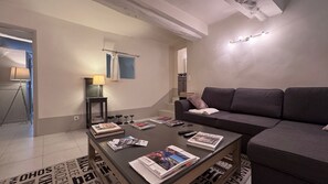 A modern living room with a sofa, coffee table, and lamp. - In the heart of the historic village, you'll find absolute peace and quiet. (Saint-Paul-de-Vence)