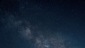Un edificio moderno con amplios ventanales, un balcón y vistas al cielo nocturno.