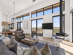 A spacious living area with a large sofa, a dining table, and a fireplace.