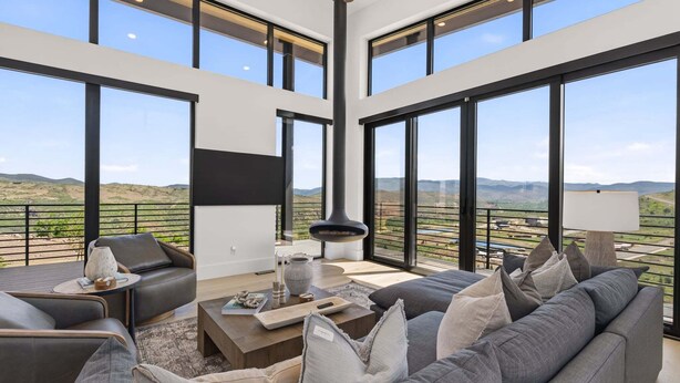 Un salón espacioso con un sofá grande, una mesa de centro y una chimenea. La habitación tiene ventanas amplias que ofrecen vistas al campo.