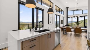 Una cocina moderna con una isla grande, armarios de madera e iluminación colgante.