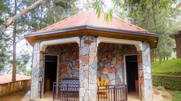 Uma construção de pedra com telhado em cerâmica, duas portas e uma pequena varanda com guarda-corpo.