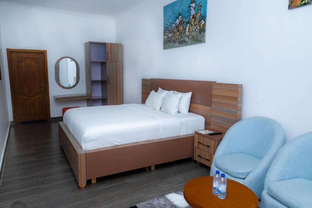 A bedroom with a bed, bedside table, chair, and a painting on the wall.