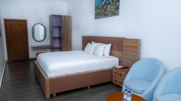 A bedroom with a bed, bedside table, chair, and a painting on the wall.