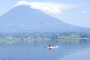 A calm lake with a person kayaking, a mountain in the background, and a clear sky.