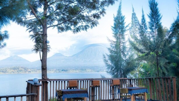 A deck with outdoor seating, overlooking a lake and mountains. - Ruhondo Beach Resort (Gashaki)