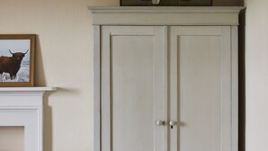 Een witte kast met twee deuren en een klein fotolijstje bovenop.
