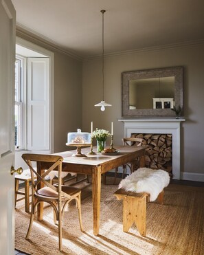 A dining room with a wooden table, chairs, a hanging light fixture, a fireplace, and a mirror on the wall. - Beautiful 4 bdrm Farmhouse with ocean views, Fife. (Kirkcaldy)