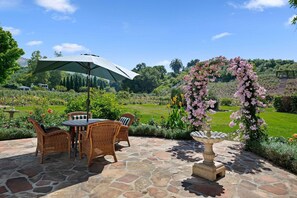 Eine Terrasse mit Steinböden, Korbmöbeln und einem Tisch mit Stühlen.