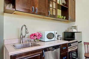 A kitchen with a sink, a microwave, a dishwasher, and wooden cabinets. - Rosebud - Blooming Rose Farm (Carpinteria)
