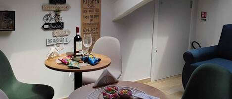 A dining area with a skylight, a table with a placemat, chairs, and wall signs including 'CAFE' and 'KITCHEN Rules'.