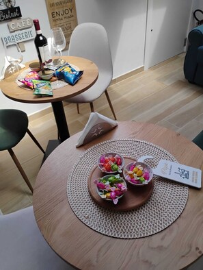 A dining area with a round table, a bottle of wine, snacks, and a menu. - Pepè attic room Naples Central (Napoli)
