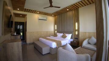 A hotel room with a bed, two bedside tables, a sofa, a chair, a ceiling fan, and an air conditioning unit.