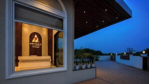 A modern building with a reception desk, potted plants, and a paved outdoor area. - Amritara The Samagam (Pindra)