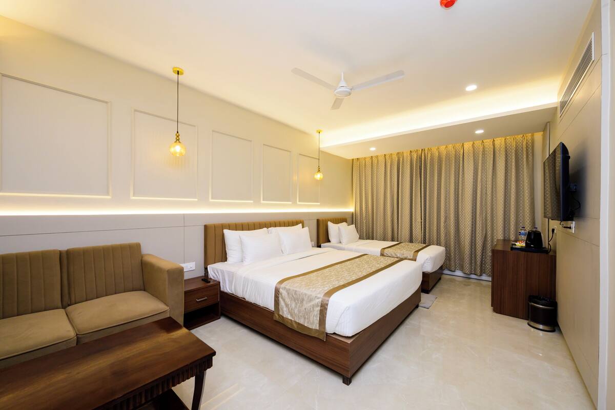 Una habitación de hotel con cama, sofá, televisión y ventilador de techo.