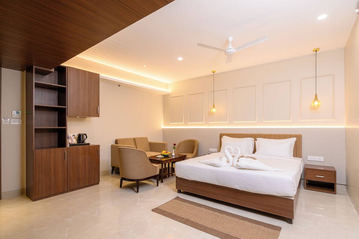 Una habitación de hotel moderna con cama, escritorio, silla, armario y ventilador de techo.