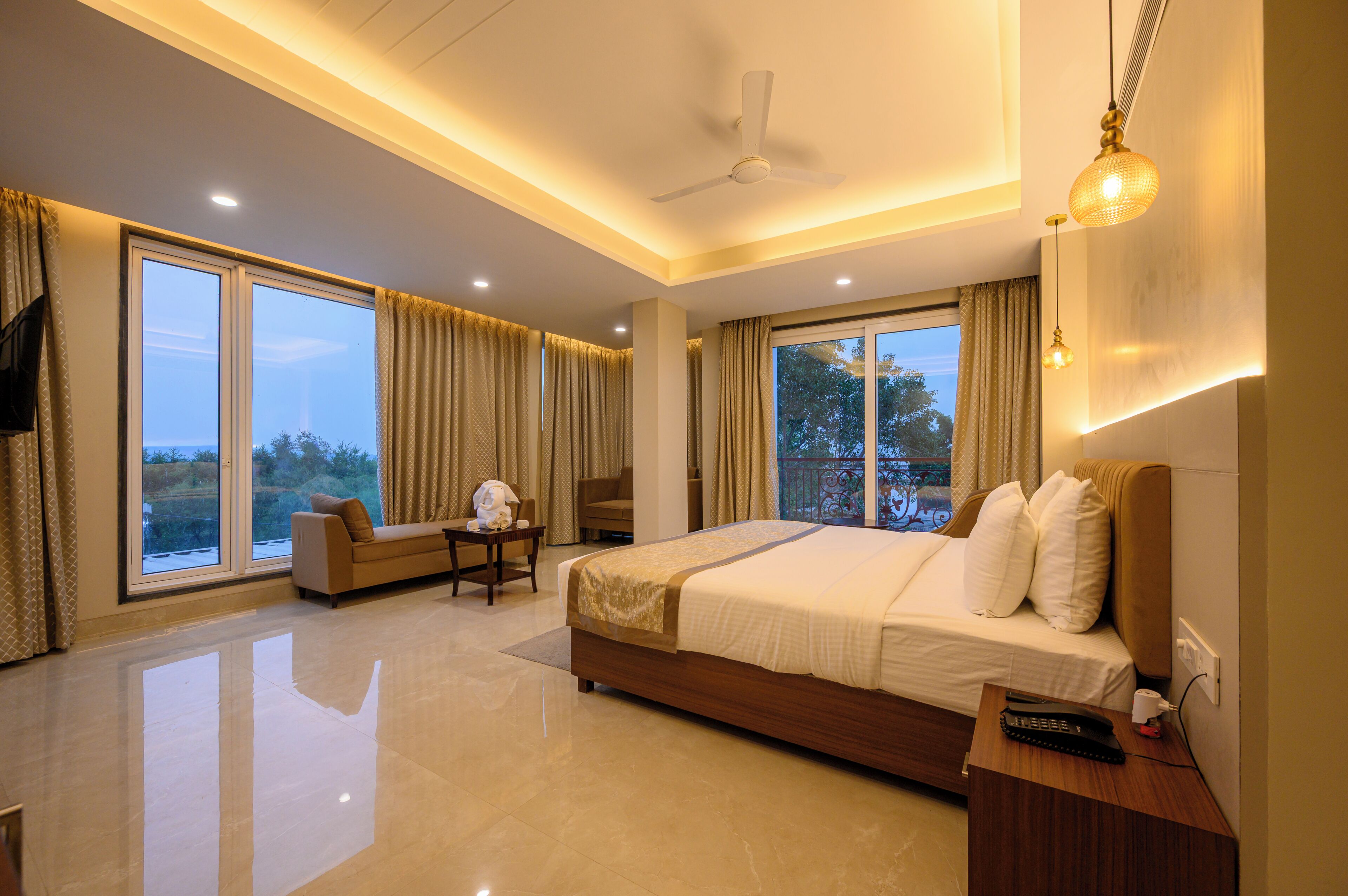 A modern hotel room with a large bed, a sofa, a small table, and a TV.