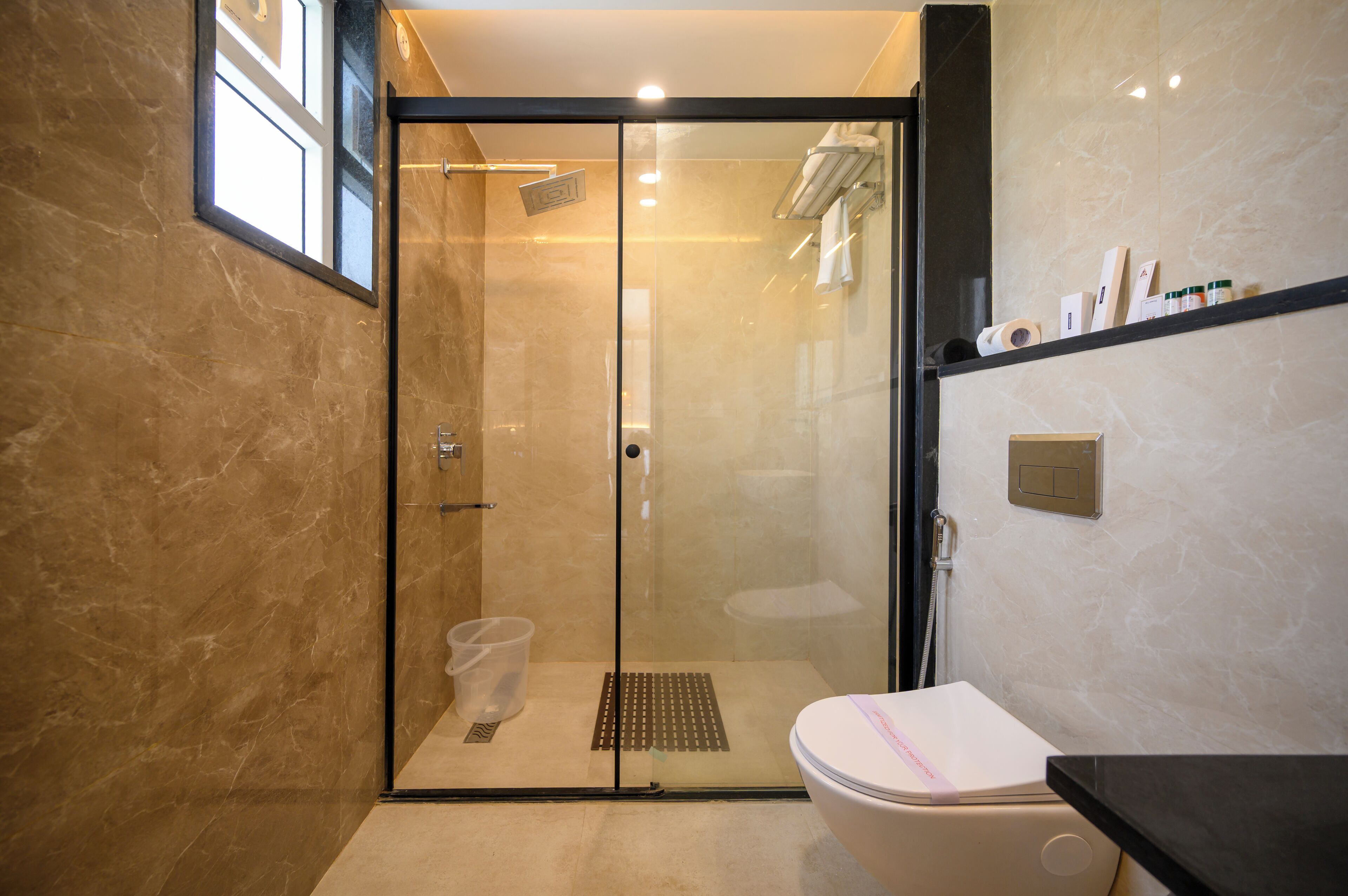 A modern bathroom with a glass-enclosed shower, a toilet, and a sink.