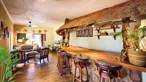 Un'area bar con un design rustico, caratterizzata da un tetto di paglia e sgabelli da bar in legno.