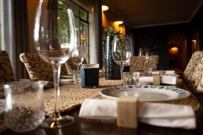 A dining table set with plates, glasses, and a vase. - Parsons River Camp (Hoedspruit)