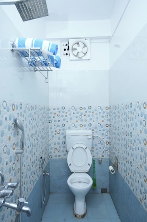 A bathroom with a toilet, shower, and a towel rack. - Sea Pearl Homestay Andaman (Port Blair)