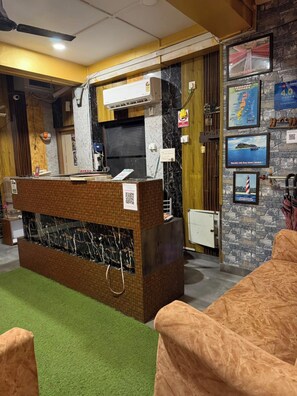 A reception desk with a marble counter, a small aquarium, and a QR code sign. - Sea Pearl Homestay Andaman (Sri Vijaya Puram)