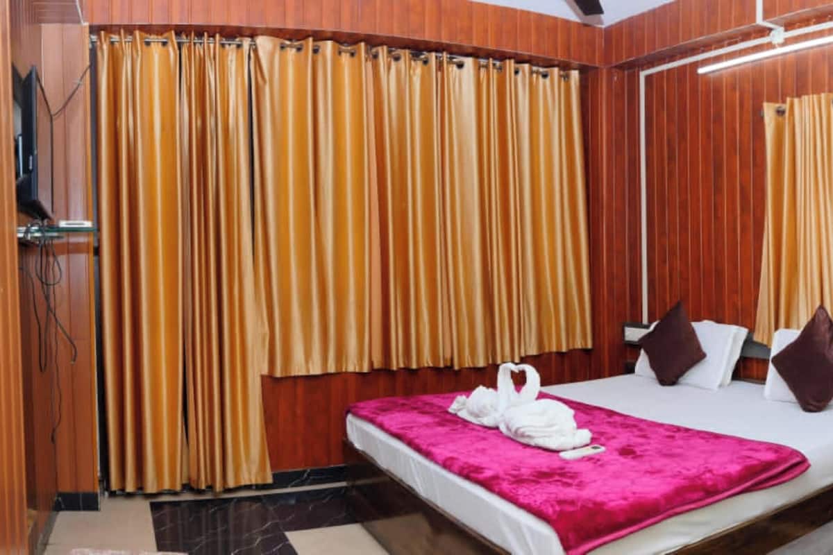 A hotel room with a bed, curtains, a wardrobe, and a window.