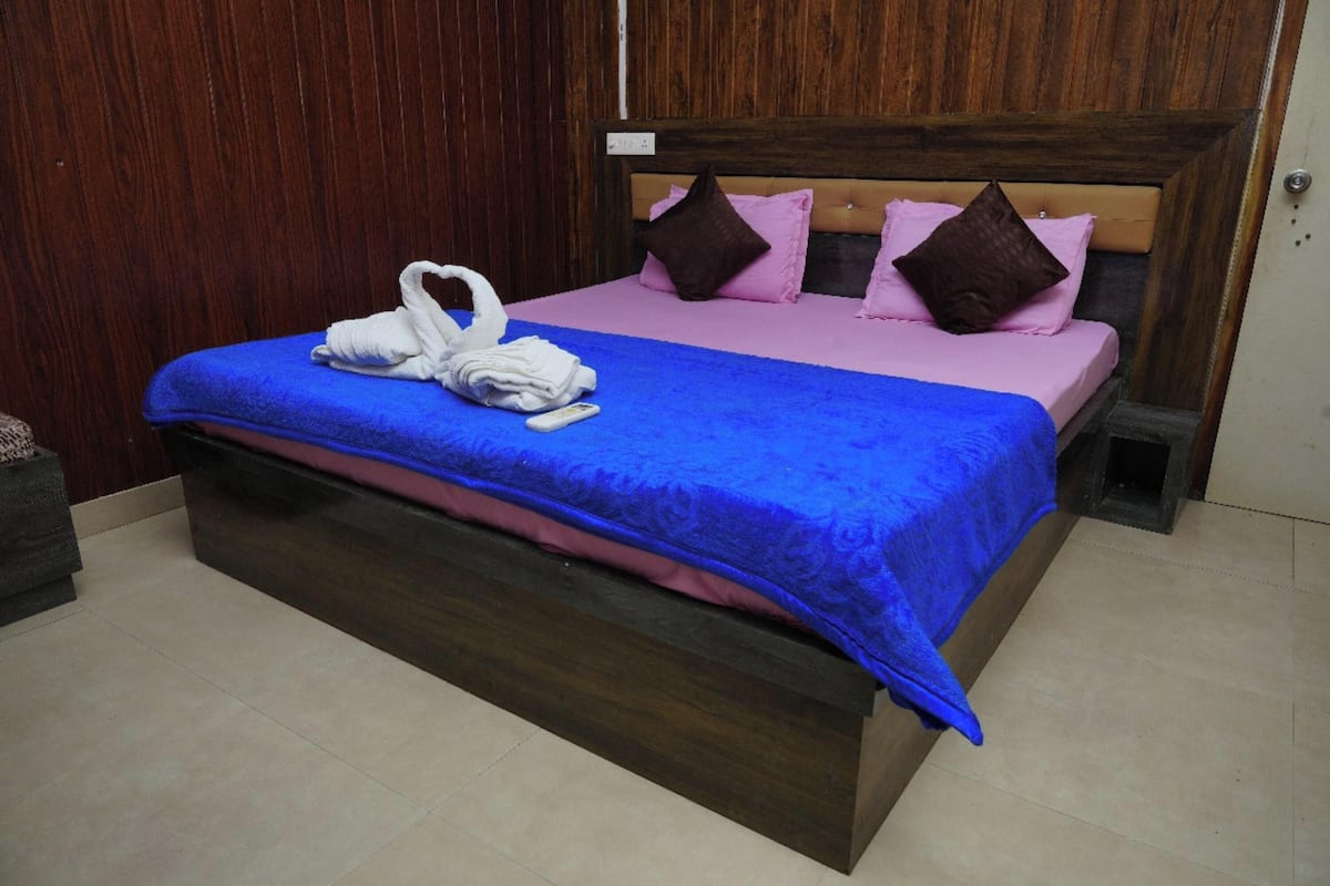 A neatly made bed with a blue bedspread, two pillows, and a white towel.