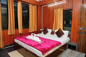 A hotel room with a wooden paneled wall, a bed with a pink blanket, and curtains on the windows. - Sea Pearl Homestay Andaman (Sri Vijaya Puram)