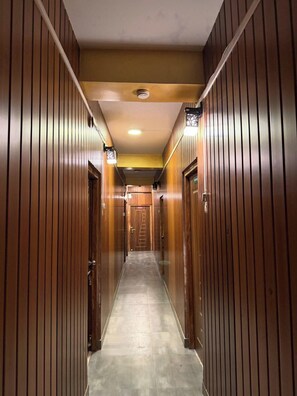 Un passadís amb panells de fusta, un paviment de rajoles i una porta al final.