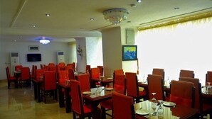 Un comedor con mesas y sillas, una araña y obras de arte en las paredes.
