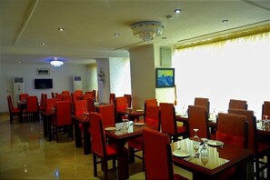 A dining area with tables and chairs, a chandelier, and artwork on the walls. - Spring Park Yaad Hotel (Lagos)